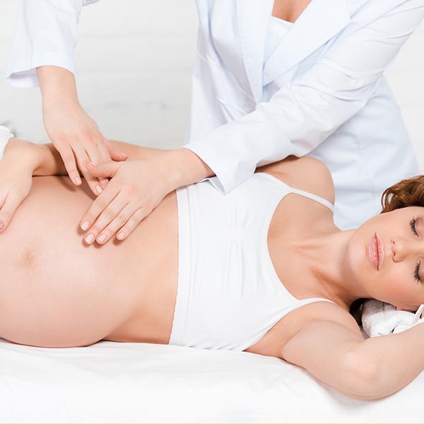 masseuse massaging a pregnant woman on massage table